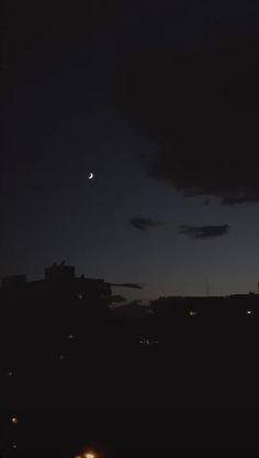 the moon is seen in the night sky over some buildings and cars parked on the street