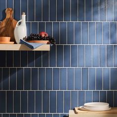 a blue tiled wall in a kitchen with plates and bowls on the shelf next to it