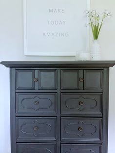 a black dresser with drawers and flowers on top