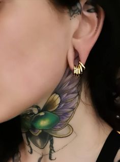 a close up of a person with tattoos on their neck and behind them is an ear piercing