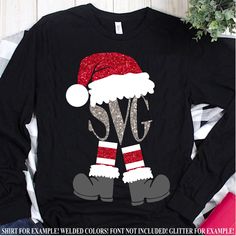 a black shirt with glitter santa hat and leggings on it, sitting next to some christmas decorations