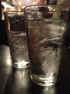 two glasses filled with water sitting on top of a table