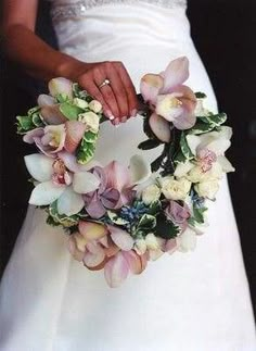 a woman in a wedding dress holding a wreath with flowers on the front and side