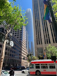 a red and white bus driving down a street next to tall buildings in a city