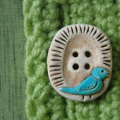 a button with a bird on it sitting on top of a green piece of cloth