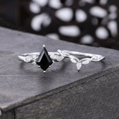 a black diamond ring sitting on top of a piece of wood with white diamonds around it