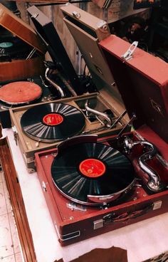 two turntables sitting on top of suitcases in a room filled with old records