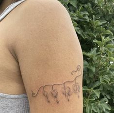 a woman with a tattoo on her arm that has three elephants drawn on it and is standing in front of some bushes