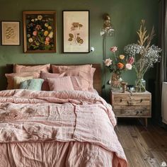 a bedroom with green walls and pink linens on the bed, flowers in vases