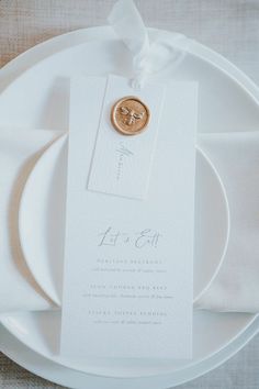 a white plate topped with a gold button on it's side next to a napkin