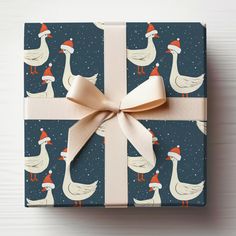 a present wrapped in blue wrapping paper with ducks and santa's hats on it