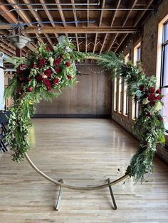 a circular arrangement of flowers and greenery on a metal stand in an empty room