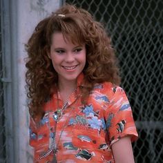 a woman with curly hair wearing an orange shirt