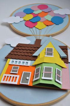 two paper houses with balloons flying over them