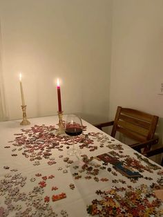 a candle is lit on a table covered with puzzle pieces