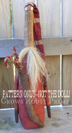 an odd looking stuffed animal with long white hair and beard sitting on top of a wooden fence