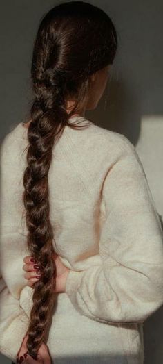 a woman with long hair standing in front of a white wall holding her hands on her hips