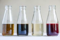 four different colored liquids in glass bottles lined up