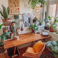 an office with plants and books on the desk in front of a large window,