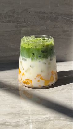 a green and white dessert sitting on top of a marble counter next to a window