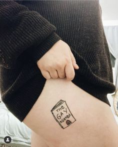 a person with a book tattoo on their thigh holding onto the back of her leg