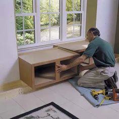 a man working on an entertainment center in a room with white tile flooring and large windows