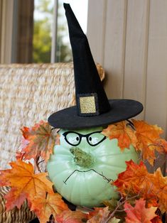 a green pumpkin with a black hat and glasses on it's head sitting in front of a wicker chair