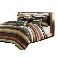 a bed with multi colored comforter and pillows