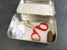 a tin with scissors and some paper in it