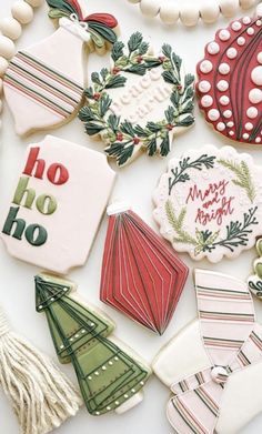 decorated christmas cookies are laid out on a white surface with holiday decorations and tassels