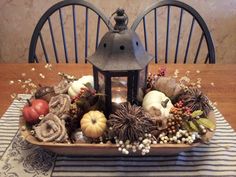 a table topped with a lantern and fall decorations