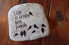 a rock with birds painted on it that says life is better with friends