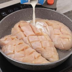 raw fish being poured into a frying pan on top of an electric burner