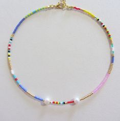 Real pearl necklace, Seed bead choker, Small pearl necklace, Rainbow jewelry Beaded choker, pearls choker, rainbow bead choker, choker necklace, colorful choker, seed bead choker, Boho choker, beach jewelry, hippie Measure the length of your neck with a measuring tape or you can use any thread, rope, or cable for telephone and after apply the measurements to a regular ruler. Necklace is 13 inches with a 2 inches adjustable extender chain. 15 inches full length. The necklace is made of Czech Rainbow beads about 2.3 mm in size. And also two real freshwater  pearls about 6 mm. Note that these necklaces are handmade, so no two are exactly alike. If you want a different necklace, I can also make a custom order Cheap Rainbow Spacer Beads Jewelry, Cheap Handmade Rainbow Jewelry, Gold Beaded Chain Pearl Choker, Pearl Chain Choker With Round Beads, Dainty Gold Necklace With Colorful Beads, Gold Pearl Beaded Necklaces With Colorful Beads, Pearl Choker With Colorful Beads For Gifts, Adjustable Gold Choker With Pearl Charm, Gold Beaded Pearl Chain Choker Necklace