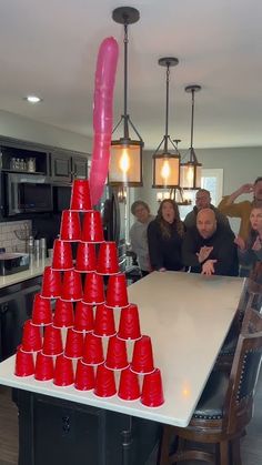 a group of people standing around a table with red cups on it and a pink object sticking out of the top