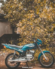 a blue motorcycle parked in front of some trees