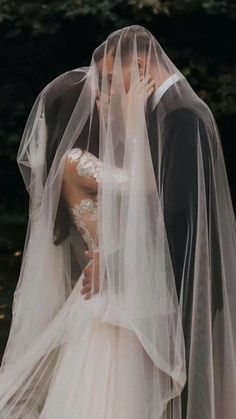 a bride and groom kissing under a veil