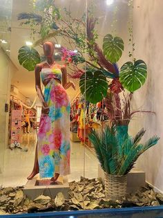 a woman's dress is displayed in front of a window with potted plants