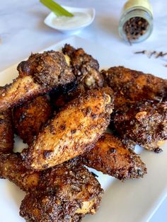 chicken wings on a white plate next to spices