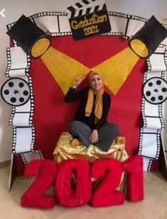 a woman sitting on top of a giant red and yellow sign with the numbers 2012 in front of her