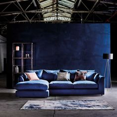 a large blue couch sitting in front of a book shelf on top of a rug