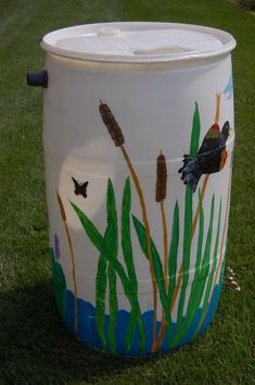 a painted trash can sitting in the grass with a butterfly on it's side