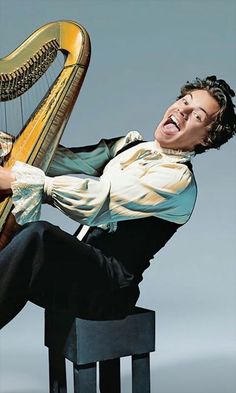 a man sitting on top of a chair holding a harp