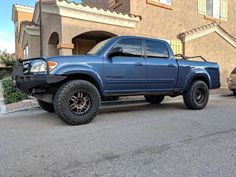 a blue pick up truck parked in front of a house