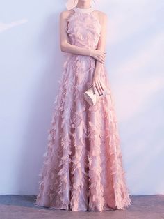 a woman in a long pink dress standing next to a wall with her hand on her hip