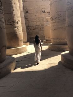 a woman in white dress walking through an egyptian temple