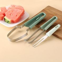 four pieces of fruit sitting on top of a cutting board next to a knife and fork