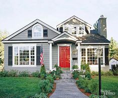 a red door sits in front of a gray house