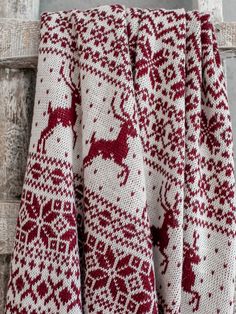 a red and white knitted blanket hanging on a wall