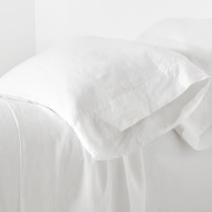 a bed with white sheets and pillows on it